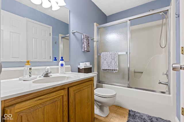 full bathroom featuring bath / shower combo with glass door, vanity, wood-type flooring, a textured ceiling, and toilet