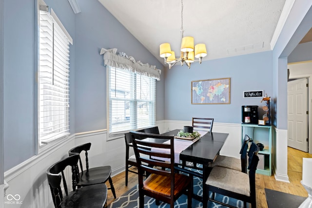 dining space featuring lofted ceiling, a notable chandelier, and wood-type flooring