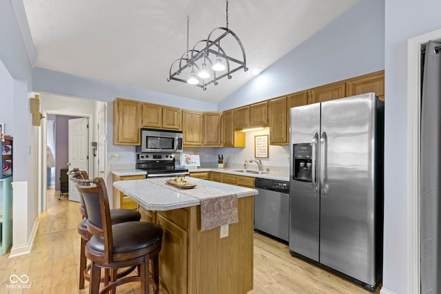 kitchen featuring appliances with stainless steel finishes, a center island, sink, and light hardwood / wood-style flooring