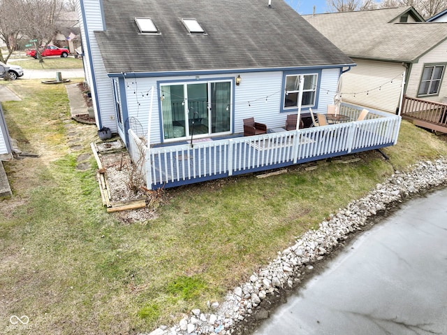 rear view of house featuring a wooden deck and a lawn