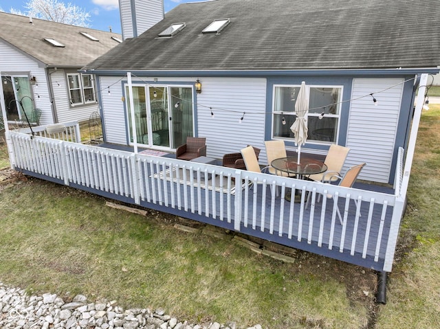 rear view of house with a wooden deck and a lawn