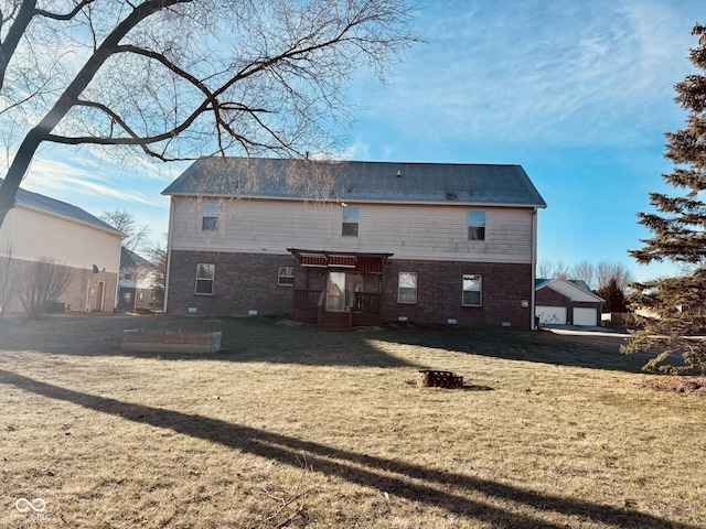 back of house featuring a garage, crawl space, brick siding, and a yard