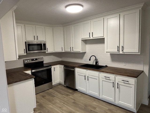 kitchen featuring tasteful backsplash, sink, white cabinets, stainless steel appliances, and light wood-type flooring