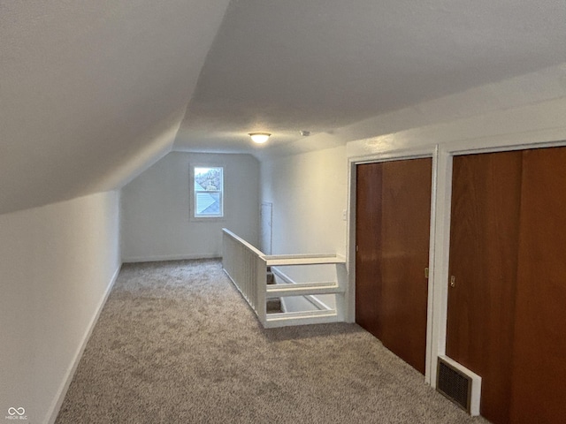 bonus room with lofted ceiling and light colored carpet