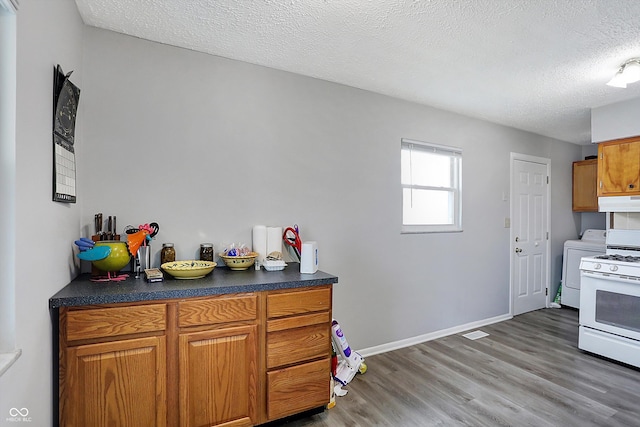 kitchen with white gas range, washer / clothes dryer, hardwood / wood-style floors, and a textured ceiling