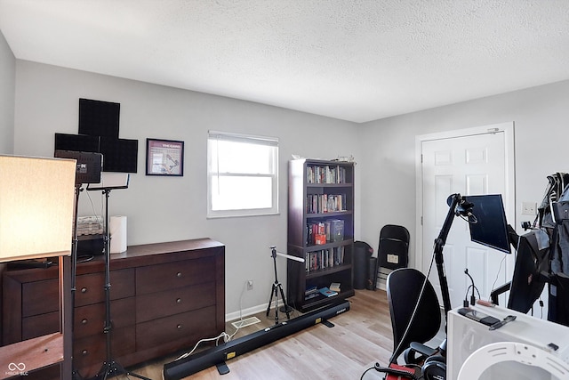 exercise room featuring a textured ceiling and light hardwood / wood-style floors