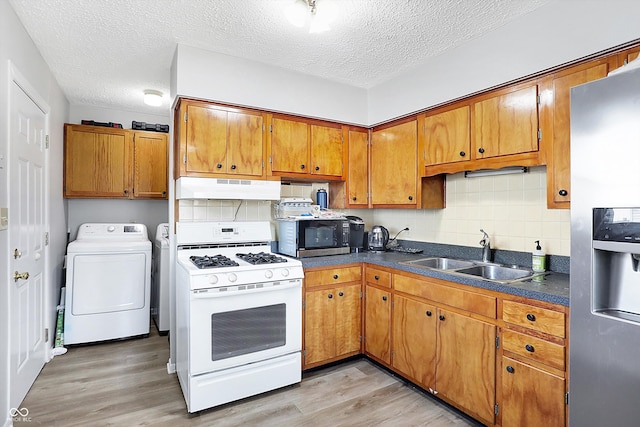 kitchen featuring sink, a textured ceiling, stainless steel appliances, light hardwood / wood-style floors, and decorative backsplash