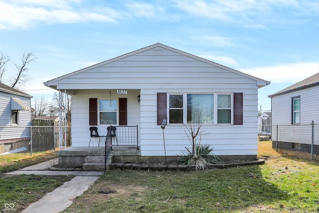 bungalow featuring covered porch and a front yard