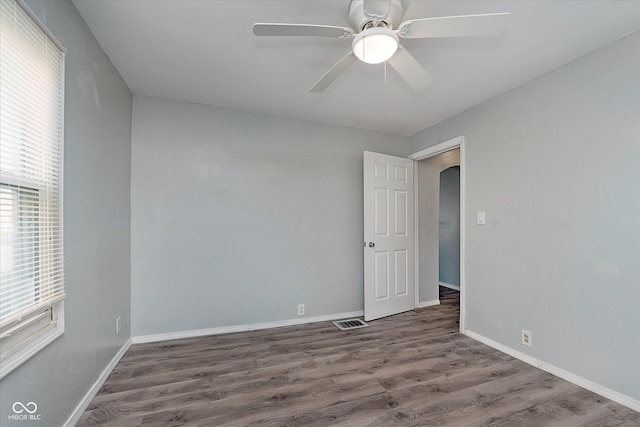 empty room with a ceiling fan, baseboards, visible vents, and wood finished floors