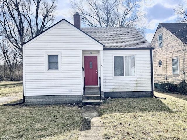 bungalow-style house with entry steps, a shingled roof, a chimney, and a front yard