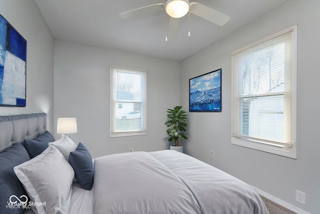 bedroom featuring multiple windows, a ceiling fan, and baseboards