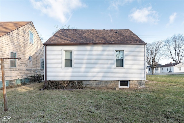 view of side of home with a lawn and roof with shingles