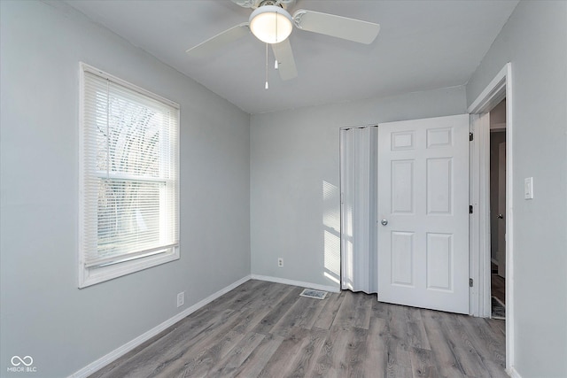 unfurnished bedroom with ceiling fan, a closet, baseboards, and wood finished floors