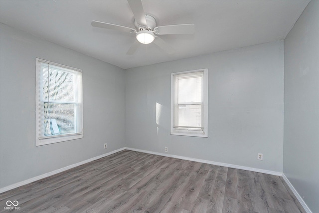 unfurnished room featuring a healthy amount of sunlight, a ceiling fan, baseboards, and wood finished floors