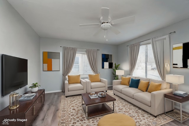 living room featuring ceiling fan, baseboards, wood finished floors, and a healthy amount of sunlight