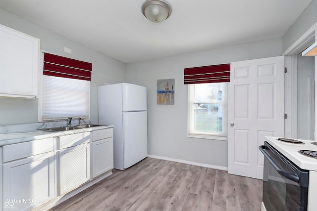 kitchen with light wood-type flooring, light countertops, a sink, and freestanding refrigerator