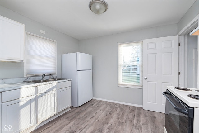 kitchen featuring light countertops, light wood-type flooring, a sink, and freestanding refrigerator