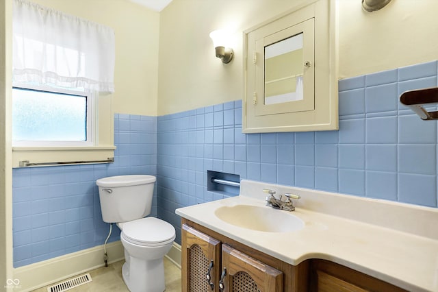 bathroom with vanity, tile walls, and toilet