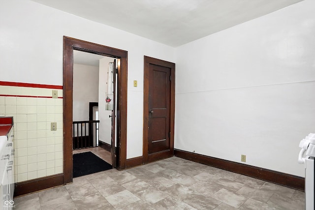 unfurnished room featuring tile walls