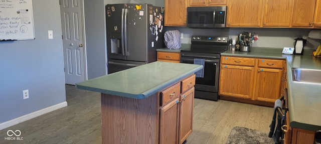 kitchen featuring a kitchen island, appliances with stainless steel finishes, and hardwood / wood-style flooring