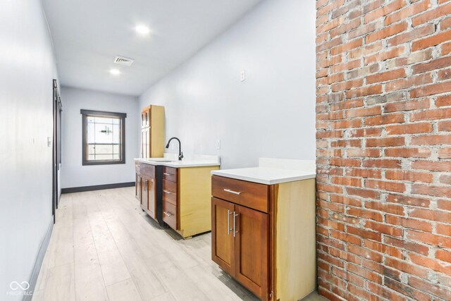 3707 N Kenwood Ave, Indianapolis, IN 46208 - bar with brick wall, a kitchen island with sink, sink, and light wood-type flooring