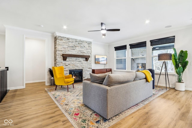 living room featuring crown molding, a stone fireplace, ceiling fan, and light hardwood / wood-style flooring