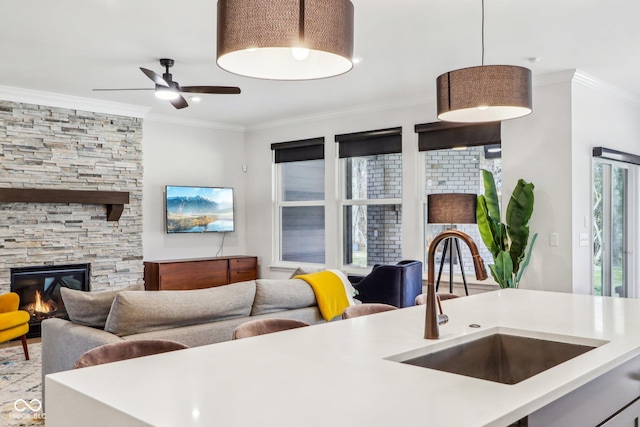 interior space featuring sink, crown molding, a fireplace, and ceiling fan