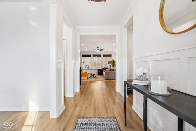 hall with ornamental molding and light wood-type flooring