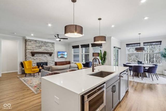 kitchen featuring an island with sink, sink, pendant lighting, and ornamental molding