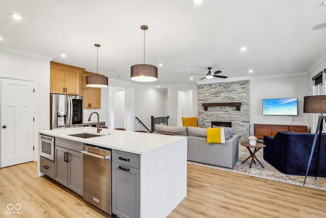 kitchen with pendant lighting, sink, appliances with stainless steel finishes, gray cabinetry, and a center island with sink