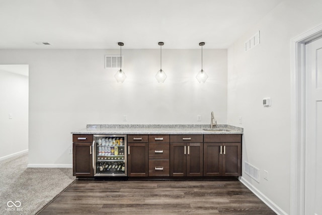 bar with wine cooler, sink, decorative light fixtures, and dark brown cabinetry