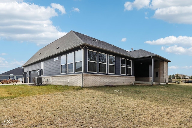 back of house featuring a garage, a yard, and central air condition unit