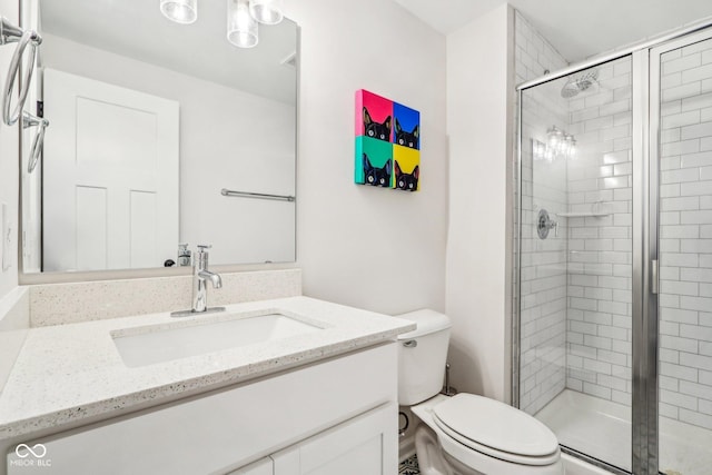 bathroom with vanity, a shower with door, and toilet