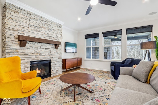 living room featuring crown molding, ceiling fan, a fireplace, and light hardwood / wood-style floors