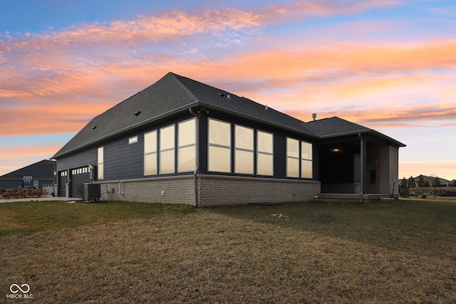 property exterior at dusk with a yard and central AC