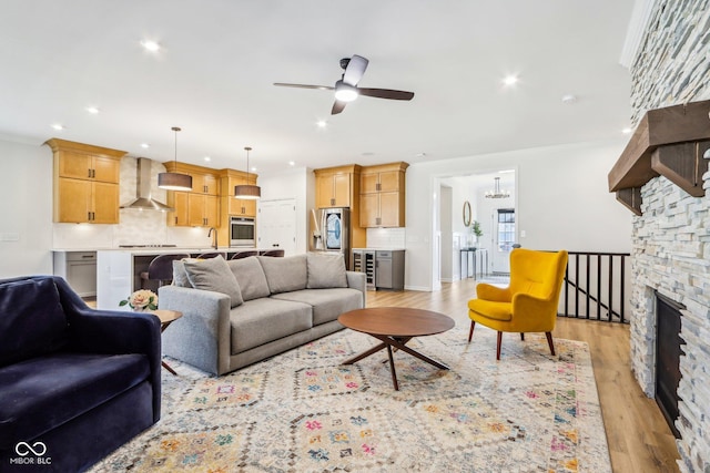 living room featuring sink, crown molding, ceiling fan, light hardwood / wood-style floors, and beverage cooler