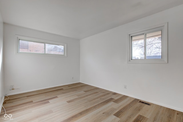 spare room featuring a healthy amount of sunlight, light wood-style floors, and baseboards