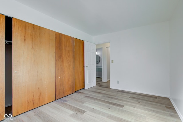 unfurnished bedroom with a closet, baseboards, and light wood finished floors