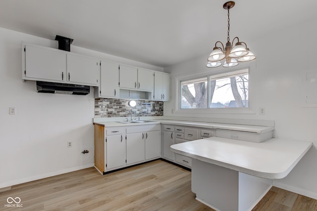 kitchen featuring a peninsula, a sink, light countertops, and decorative backsplash