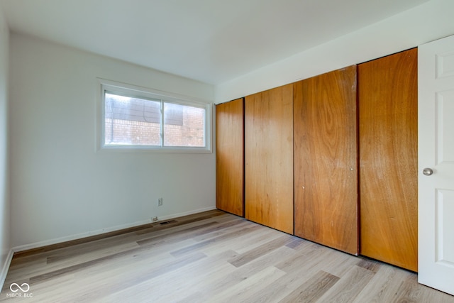 unfurnished bedroom with a closet, light wood-style flooring, and baseboards