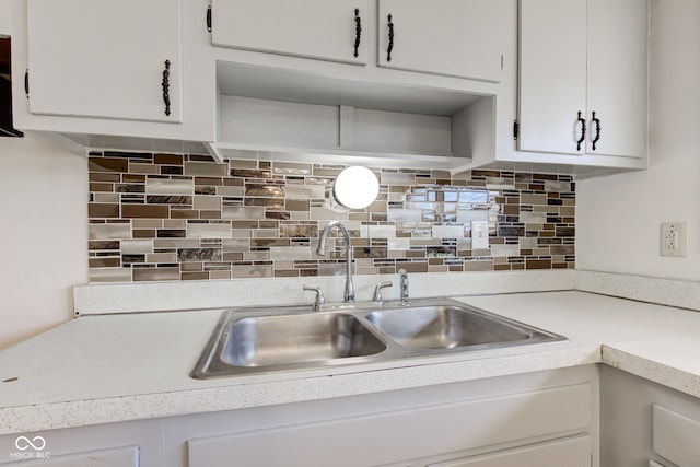 kitchen featuring a sink, white cabinets, light countertops, and decorative backsplash