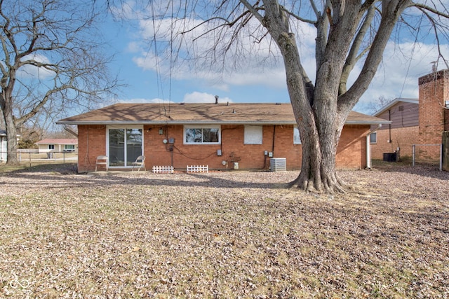 back of property featuring central AC, brick siding, and fence