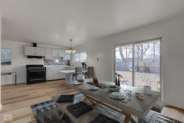 dining area featuring light wood-style floors, visible vents, and a notable chandelier