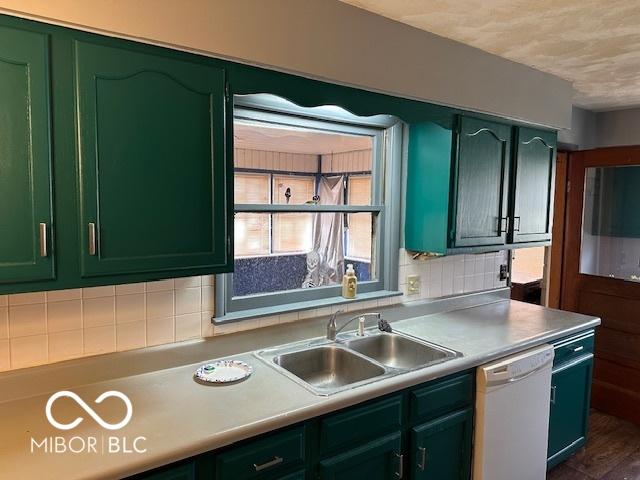 kitchen with tasteful backsplash, green cabinets, dishwasher, and sink