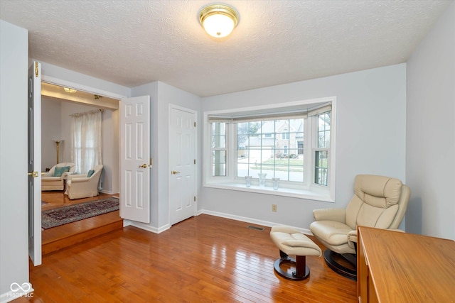 living area with hardwood / wood-style floors and a textured ceiling