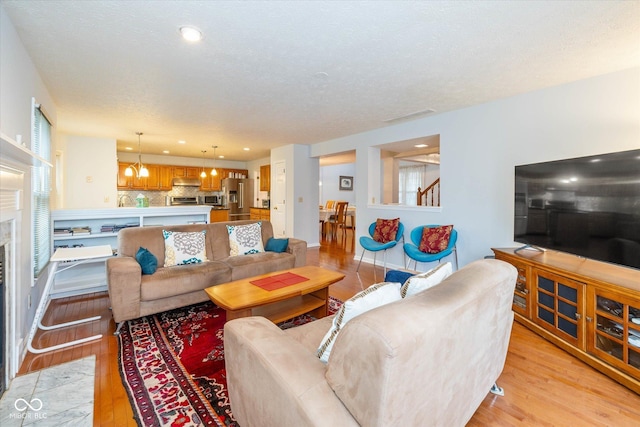 living room with a fireplace, light hardwood / wood-style floors, and a textured ceiling