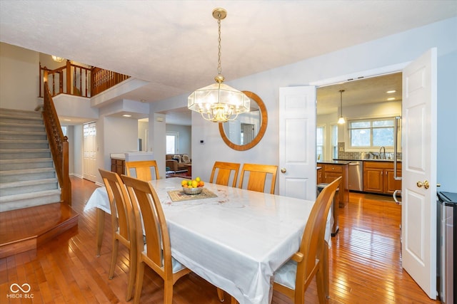 dining space with sink, an inviting chandelier, and light hardwood / wood-style flooring