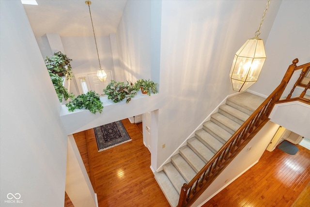 stairs with wood-type flooring and a high ceiling