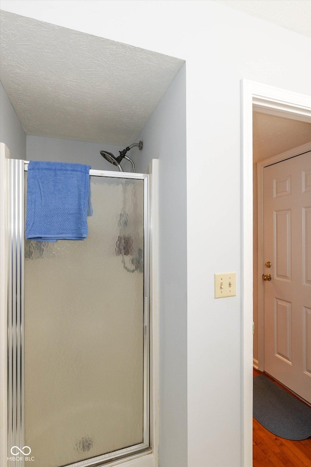 bathroom featuring hardwood / wood-style flooring, a textured ceiling, and walk in shower