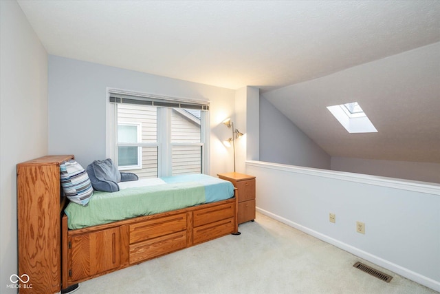 bedroom featuring lofted ceiling with skylight and light colored carpet